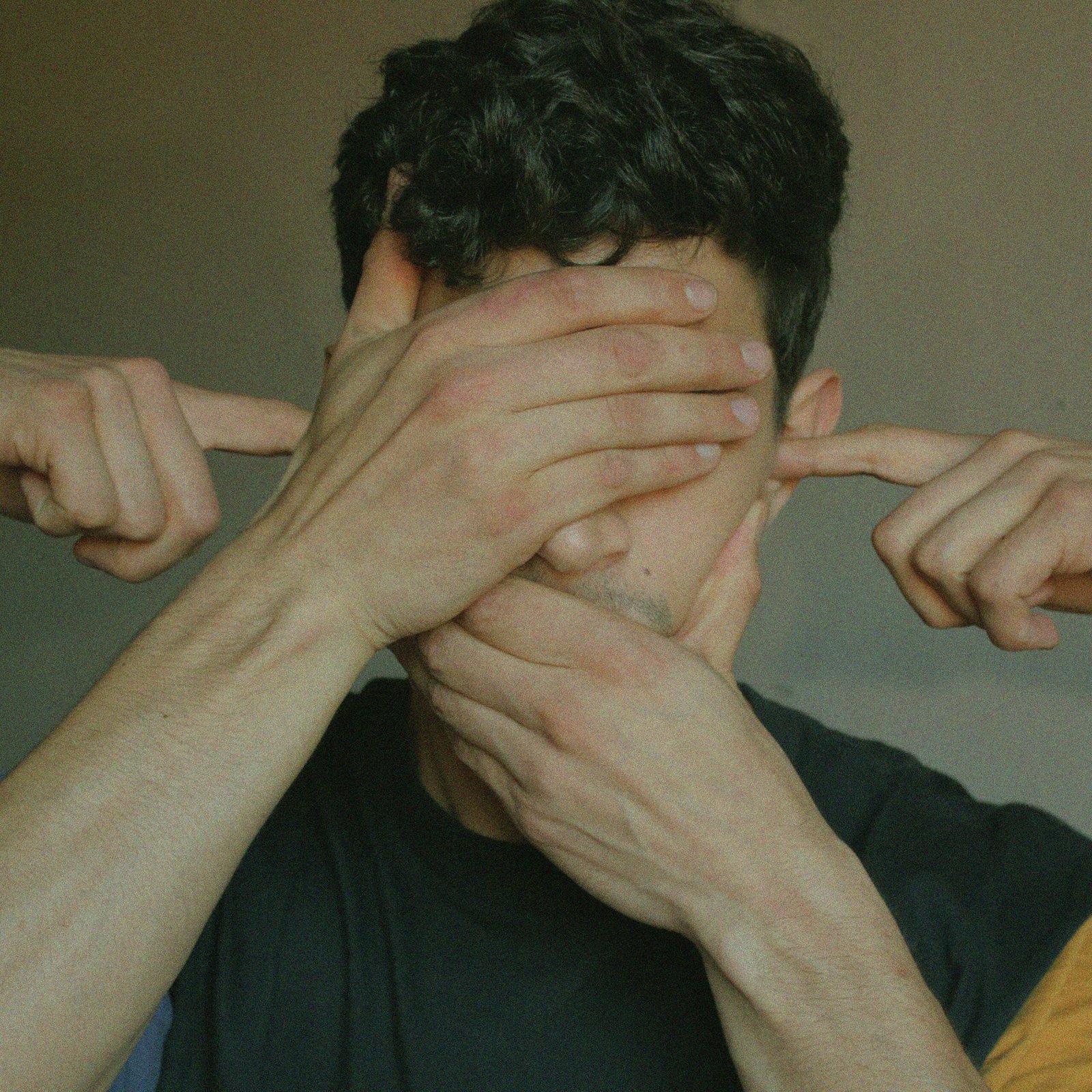 Conceptual image depicting a man with hands blocking his senses, symbolizing silence and perception blockage.